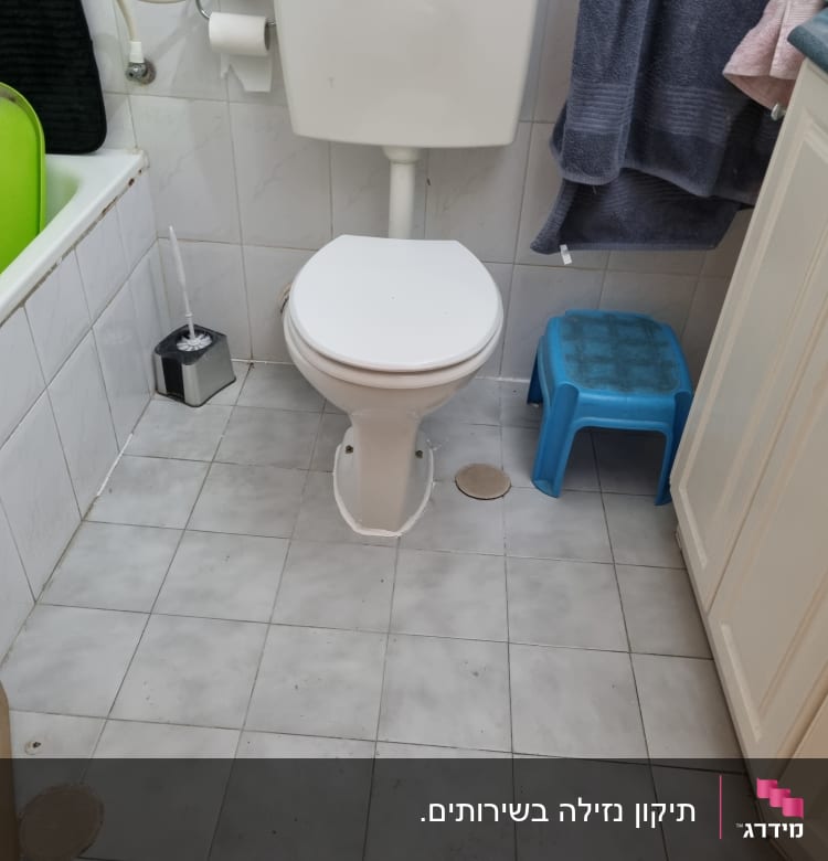 אסלה לבנה עם מיכל הדחה בחדר אמבטיה